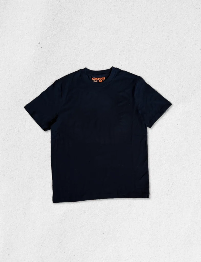 T-shirt noir à manches courtes en coton premium avec étiquette intérieure orange Custom moi ça, posé à plat sur fond clair.