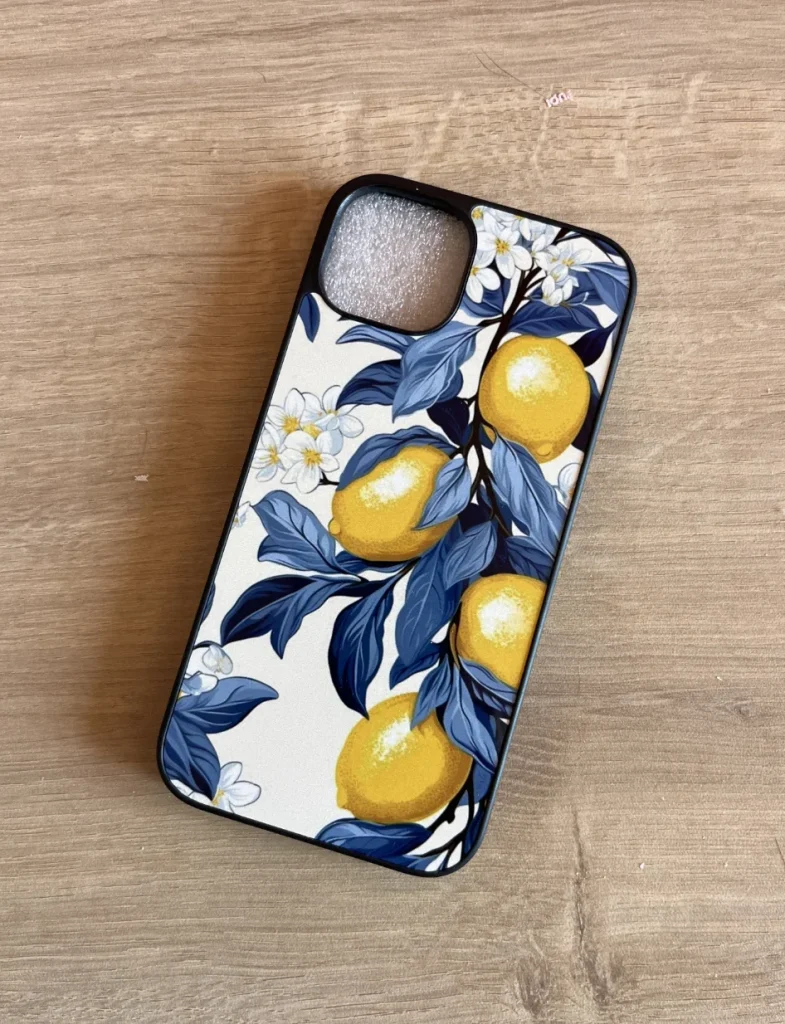 Coque d'iPhone personnalisée avec un motif floral de citronniers, citrons jaunes vifs et feuillage bleu indigo sur fond blanc cassé.