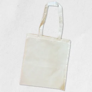 Tote bag vierge en coton naturel écru, posé à plat, prêt pour une personnalisation artisanale par broderie ou impression transfert DTF haute définition.