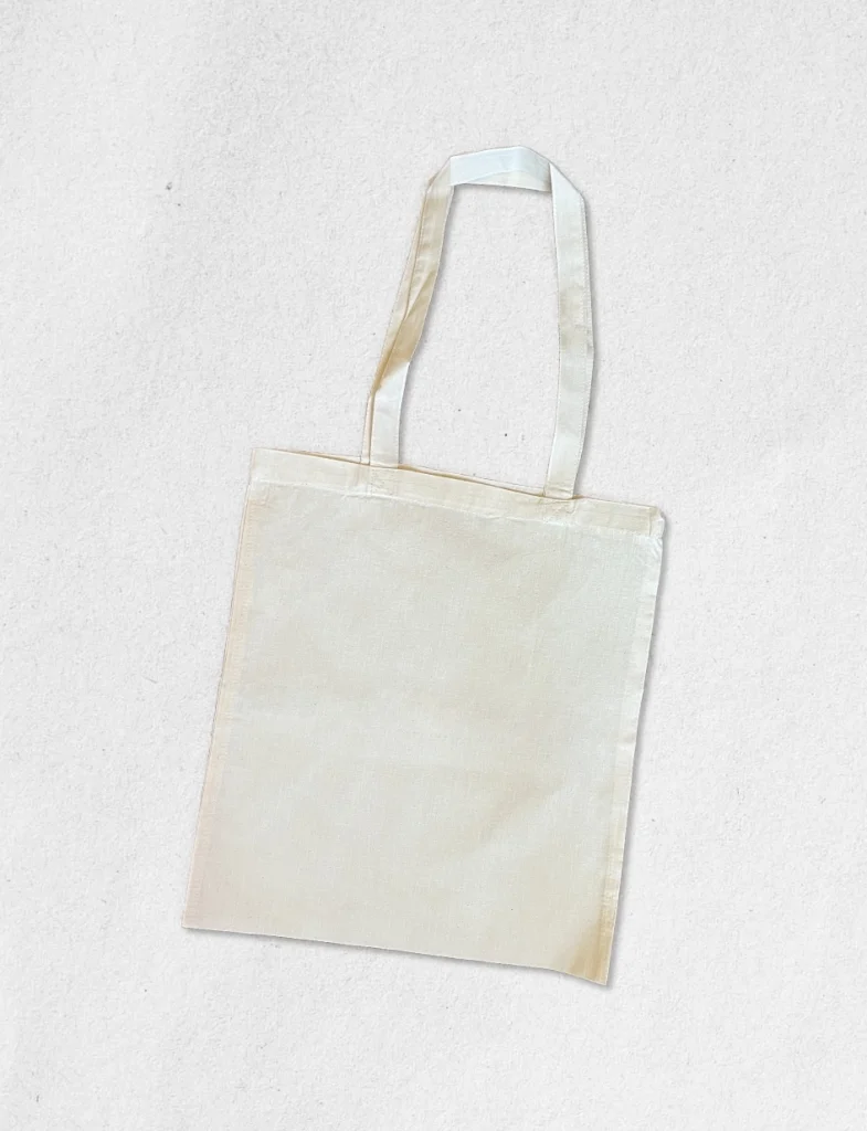 Tote bag vierge en coton naturel écru, posé à plat, prêt pour une personnalisation artisanale par broderie ou impression transfert DTF haute définition.